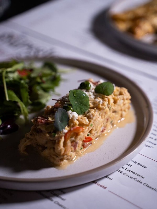 Kagianas with country sausage, cherry tomatoes, goat cheese, olive crumble, and basil oil