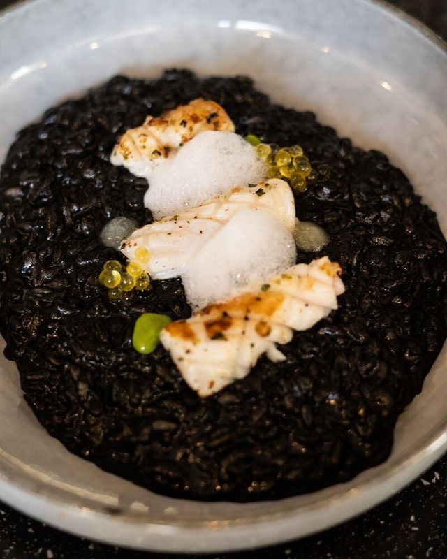 Black seafood risotto with asparagus and calamansi